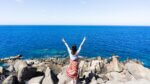 woman in white and red dress standing on rocky shore during daytime