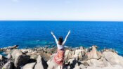 woman in white and red dress standing on rocky shore during daytime