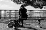 woman in black jacket and pants standing beside dog