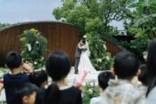 Bride and groom kiss at an outdoor wedding, children watching