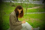 a woman sitting on a bench in the grass